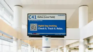Lidostas uzgaidāmās telpas monitors ar informāciju par lidojumiem un bagāžas izsekošanu.