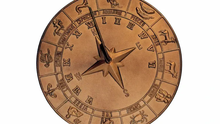 Bronzas zodiaka pulksteņa ciparnīca ar astroloģiskajām zīmēm uz balta fona.