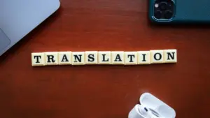 Vārds 'translation' izlikts no burtu klucīšiem uz koka galda ar tehnoloģijām.