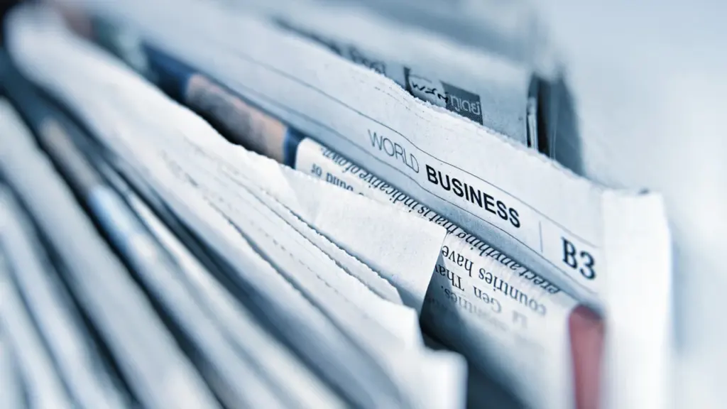 Kaudzē sakārtoti laikraksti, kuros redzama sadaļa ar uzrakstu World Business un lapaspuses numurs.